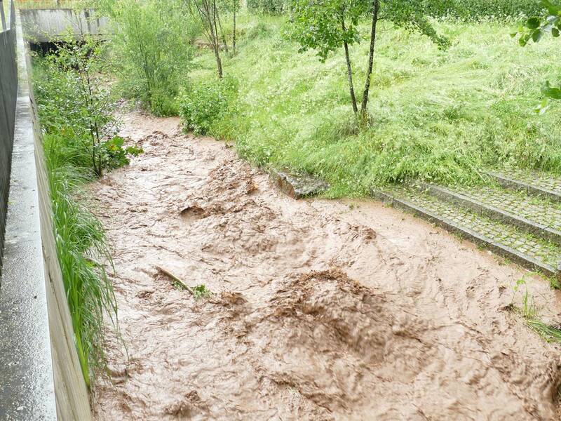 Der Ebersbach neben dem Rathaus mit hohem braunen Wasserstand während eines Starkregenereignisses