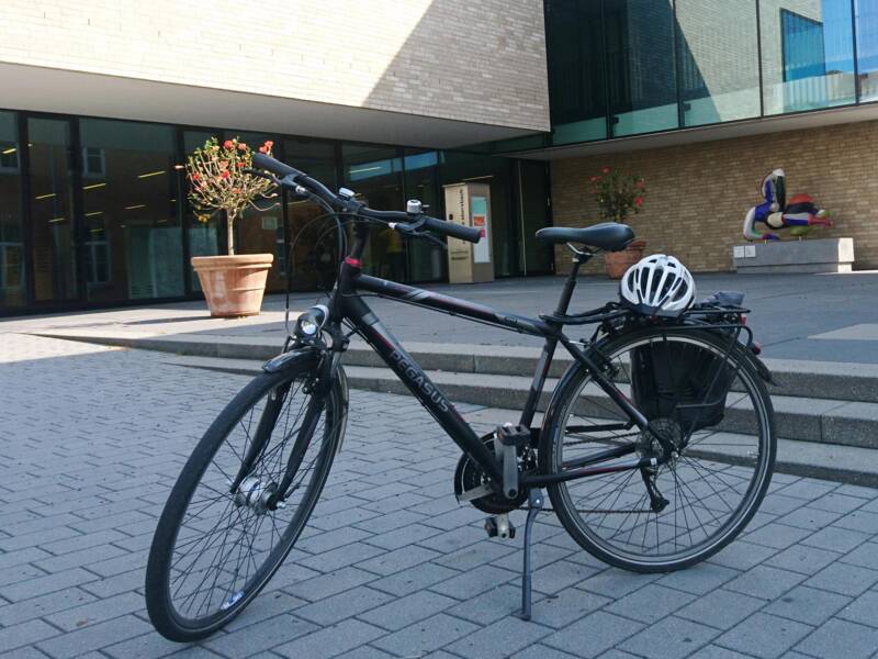 Abgestelltes schwarzes Herrenfahrrad mit weißem Helm auf dem Gepäckträger vor dem Ebersbacher Rathaus