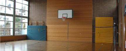 Hardtschulturnhalle Innenansicht mit Basketballkorb und Turnmatten an der Wand