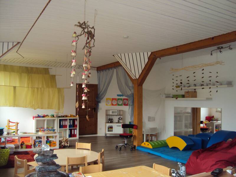 Kinderhaus Funkelstein Gruppenraum mit Spielküche, Tischen mit Stühlen und Regalen mit Spielzeug