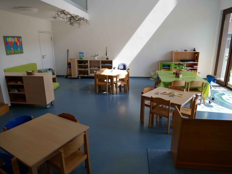 Gruppenraum mit Tischgruppen und Stühlen sowie Regalen im Kinderhaus Schatzkiste 