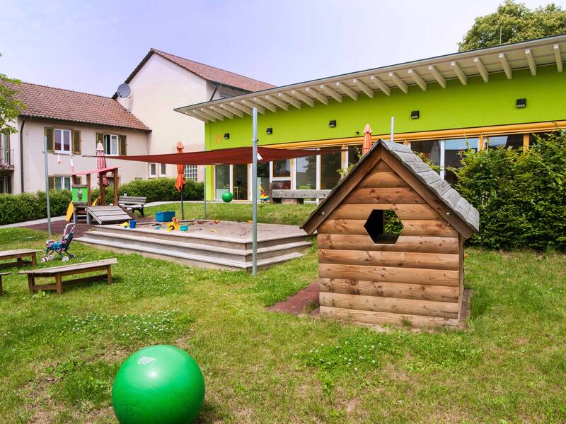 Garten der Evangelischen Kinderkrippe Zwergenstüble mit Sandkasten, Spielhaus und Sitzbänken