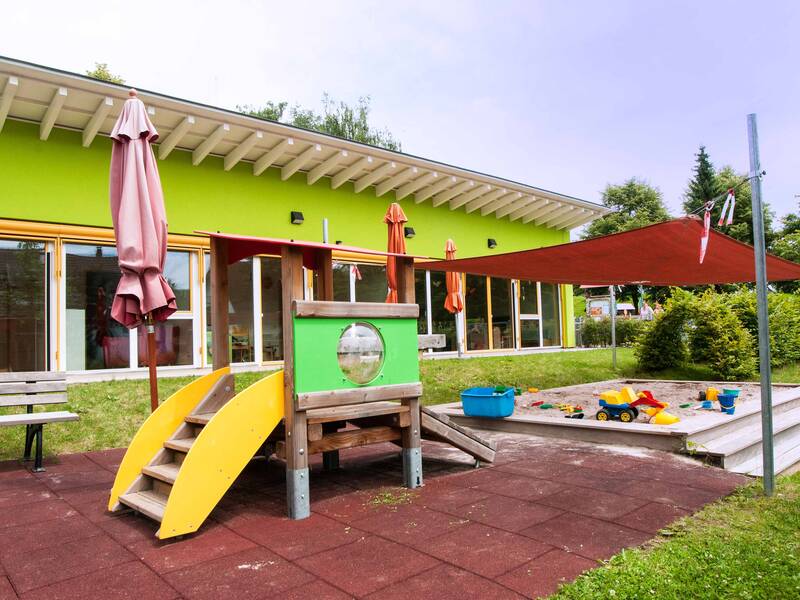 Sandkasten mit Sonnensegel und einer Kleinkindrutsche im Garten der Evangelischen Kinderkrippe Zwergenstüble