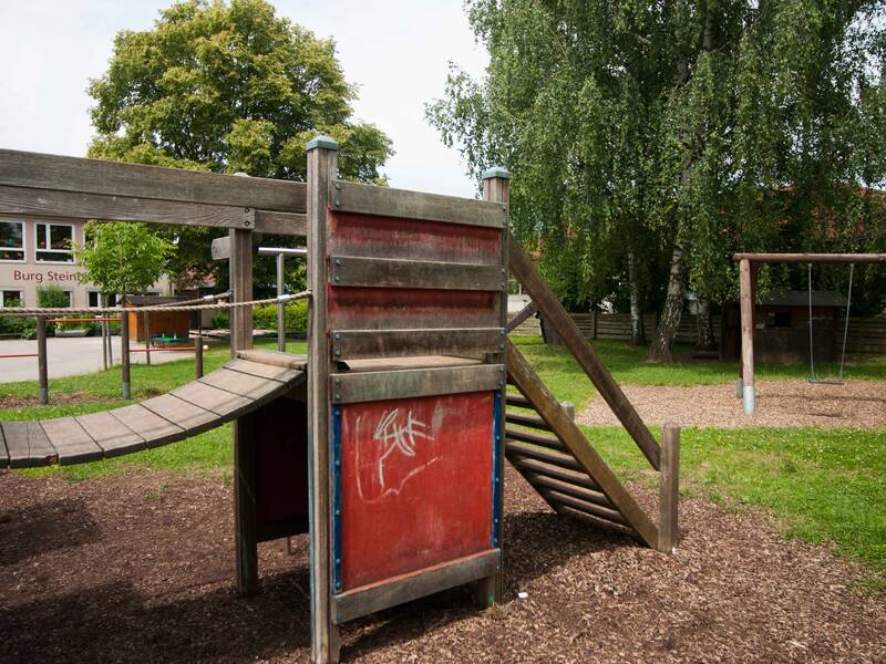 Kletterelement und Schaukel im Hintergrund auf dem Spielplatz des Kindergarten Burg Steinbiss