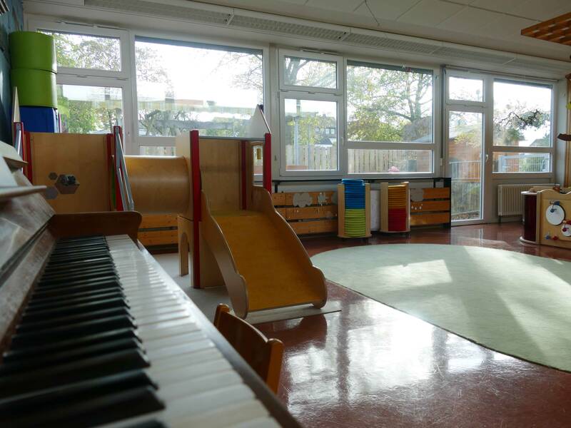  Gruppenraum mit Klavier im Vordergrund des Kindergarten Pusteblume Weiler