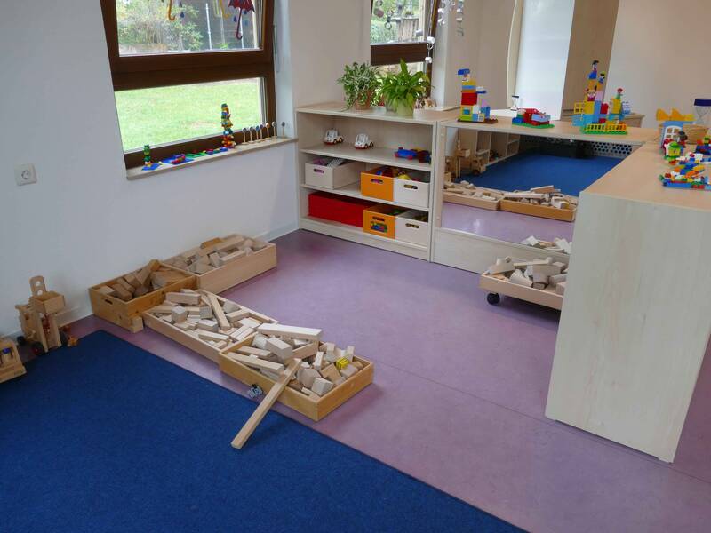 Gruppenraum im Kindergarten Ringweg in Roßwälden mit Holzregalen und vielen holzfarbenen Bauklötzen auf einem lila Teppichboden