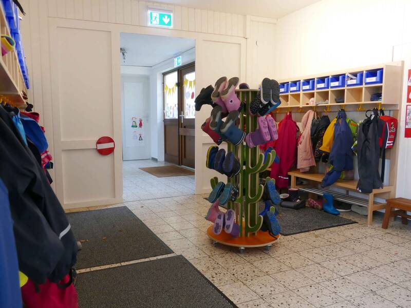 Kindergarten Ringweg Roßwälden Garderobenbereich mit vielen Jacken und einem Ständer mit bunten Kindergummistiefeln